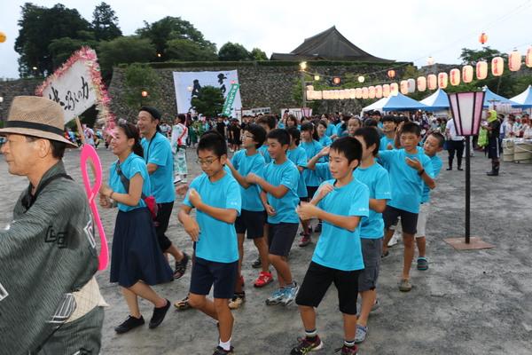 水色のシャツを着て踊る学生たちの写真