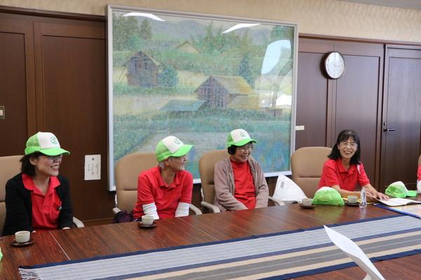 帽子にユニホーム姿の女性らが長机に座って卓球バレーの全国優勝の報告をしている写真
