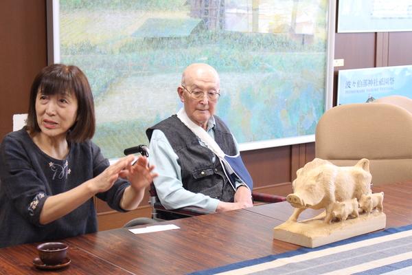 テーブルに猪の親子木彫作品が置いてあり、作品の寄贈に来られた前川修さんと娘さんの写真