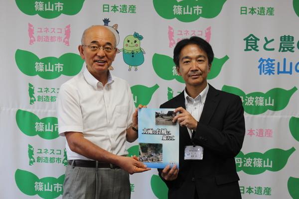 酒井市長と廣澤 純一気象台長が「大雨や台風に備えて」という冊子を一緒に持ってこちらに見せている写真