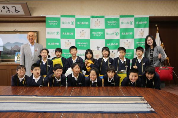 市長と女性の間に、2列に分かれて並ぶ小学生の写真