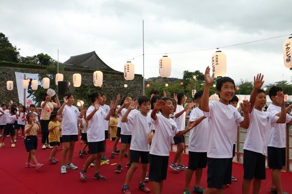体操服を着た小学生と、未就学児の子供たちが躍っている写真