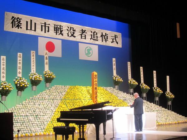 篠山市戦没者追悼式と書かれた祭壇の前で男性がマイクで祭壇に方へ向かって話をしている写真