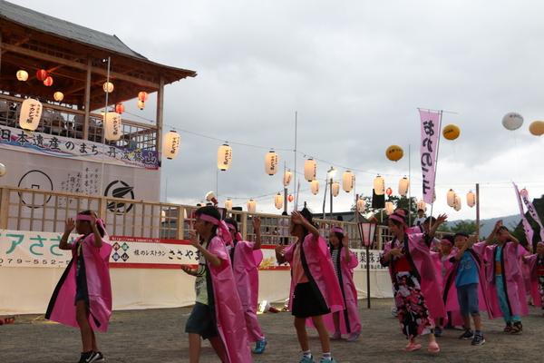 ピンク色の法被を着た子供が躍っている写真