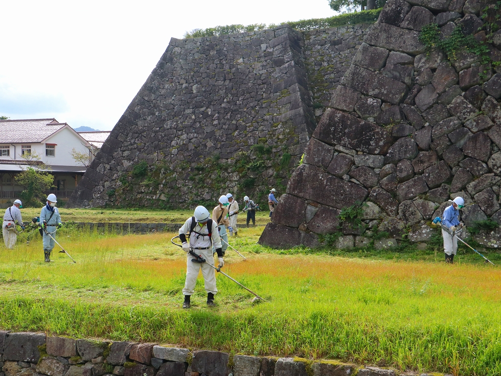 篠山城跡の石垣付近を、ヘルメットをかぶった数名の方が草刈りしている