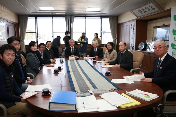 市制20周年事業検討委員会の皆さんと市長が丸いテーブルに座ってる集合写真