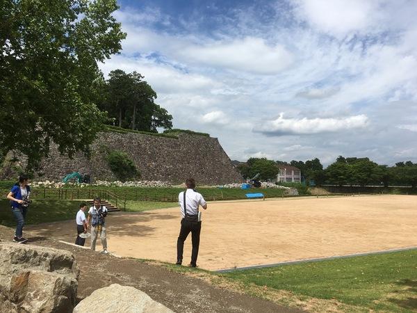 遠くから高い天守台石垣を見ながら写真を撮っている写真