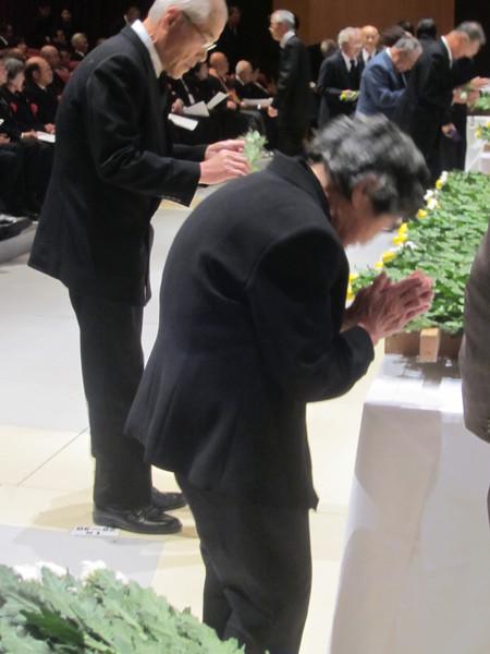 祭壇に向かって、年配の男性と女性が手を合わせて礼をしている写真