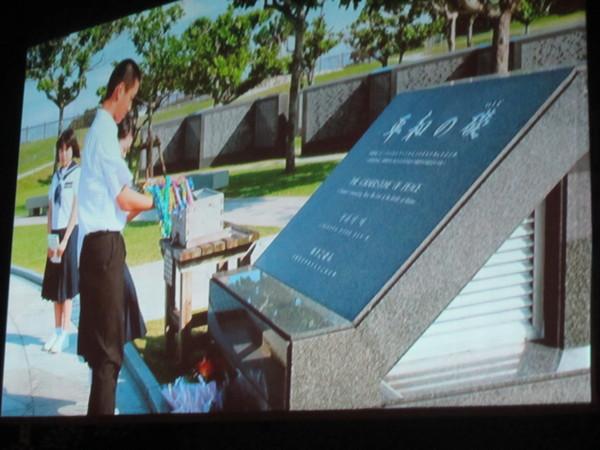 スクリーンに平和の礎と書かれた石碑と、中学生の生徒が映っている写真
