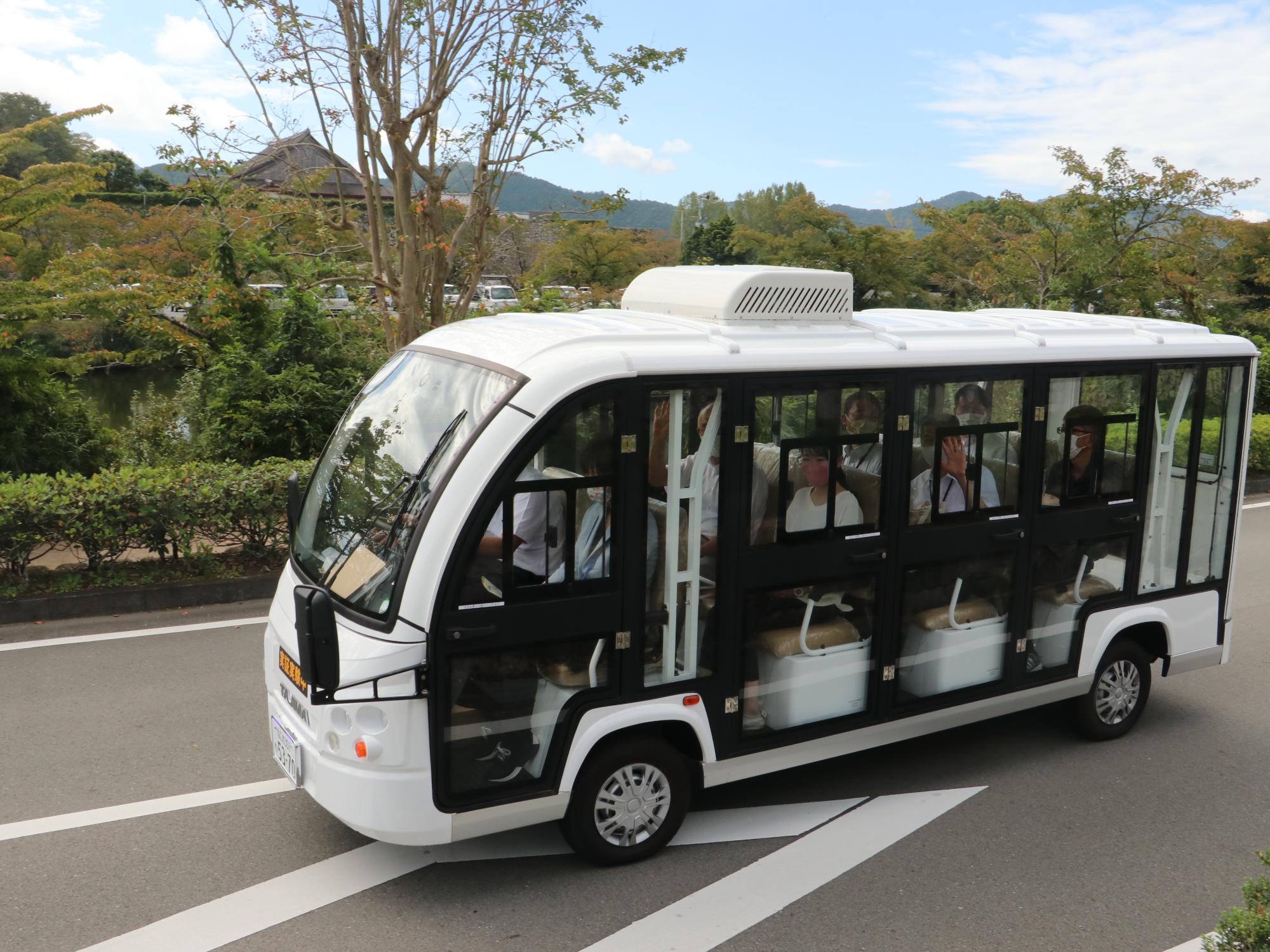 走っているグリーンスローモビリティから乗客が手を振っている