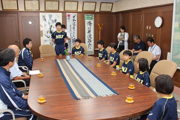 B＆G全国ジュニア水泳競技大会に出場する中学生3名と小学四4名の選手が市長室に表敬訪問に来て代表の男子が立って挨拶をしている写真