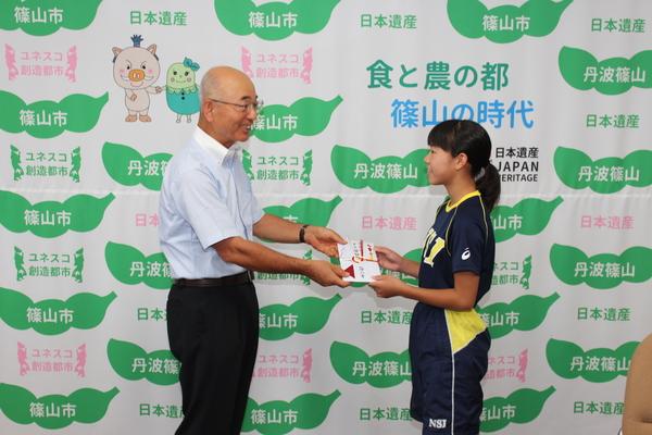 市長より選手代表の女子選手へのし袋を受け渡している写真