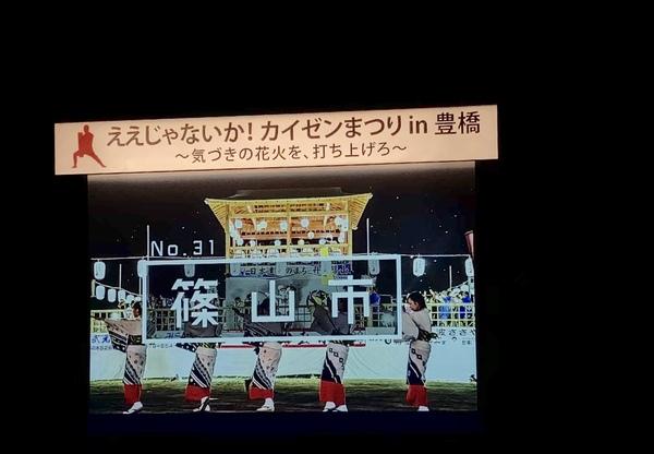 会場のスクリーンに「ええじゃないか！カイゼンまつりin豊橋~気づきの花火を、打ち上げる~篠山市と文字がかかれており、デカンショ祭りのやぐらや浴衣を着てデカンショを踊っている女性5名が映っている写真