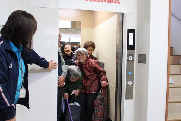完成披露式後に杖をついた高齢者がエレベーターを試乗している写真