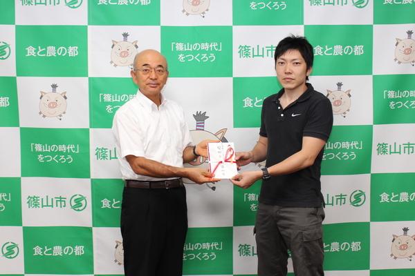 市長と園田雄一さんが祝い金を持って記念写真