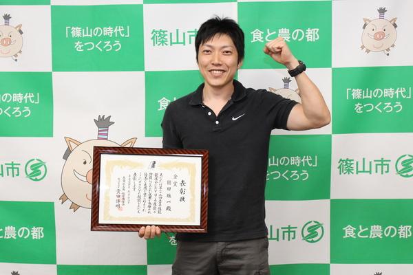 園田雄一さんが賞状を持ち、ガッツポーズしている写真