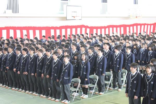 卒業生が全員で起立して歌を歌っている写真