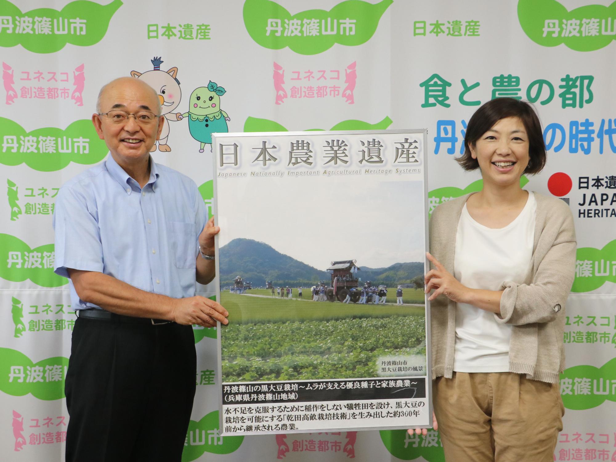 市長と女性が日本農業遺産のパネルを持っている