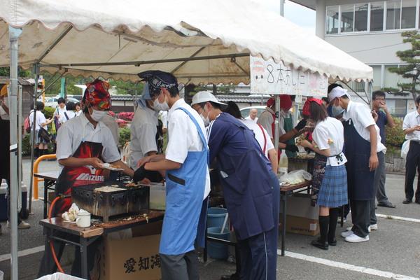 テントの中で子供達がエプロンをしてたこ焼きを焼いている写真