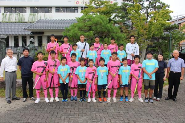 ピンクのユニフォームを着た子供達がホッケーを手に青いユニフォームを着た子供達がメダルを首にかけ一緒に記念撮影写真