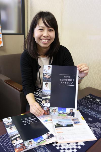 机には篠山市企業紹介ガイドブックが広げられ、女性がガイドブックを持って笑顔で紹介している写真