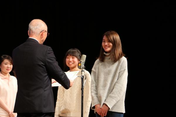 笑顔の女性2名が賞状を読み上げる市長の前に立っている写真