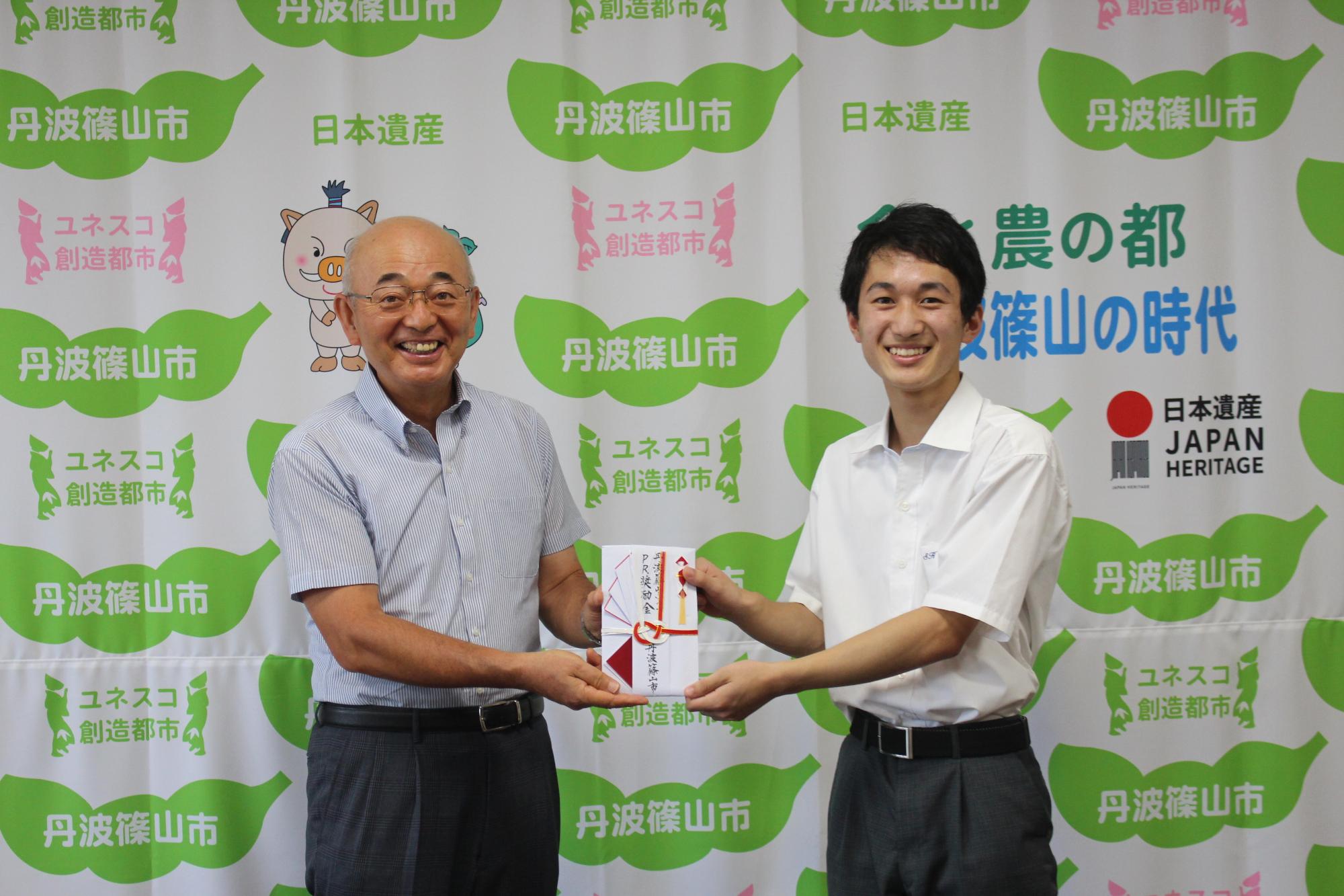 市長から奨励金を受け取る男子高校生