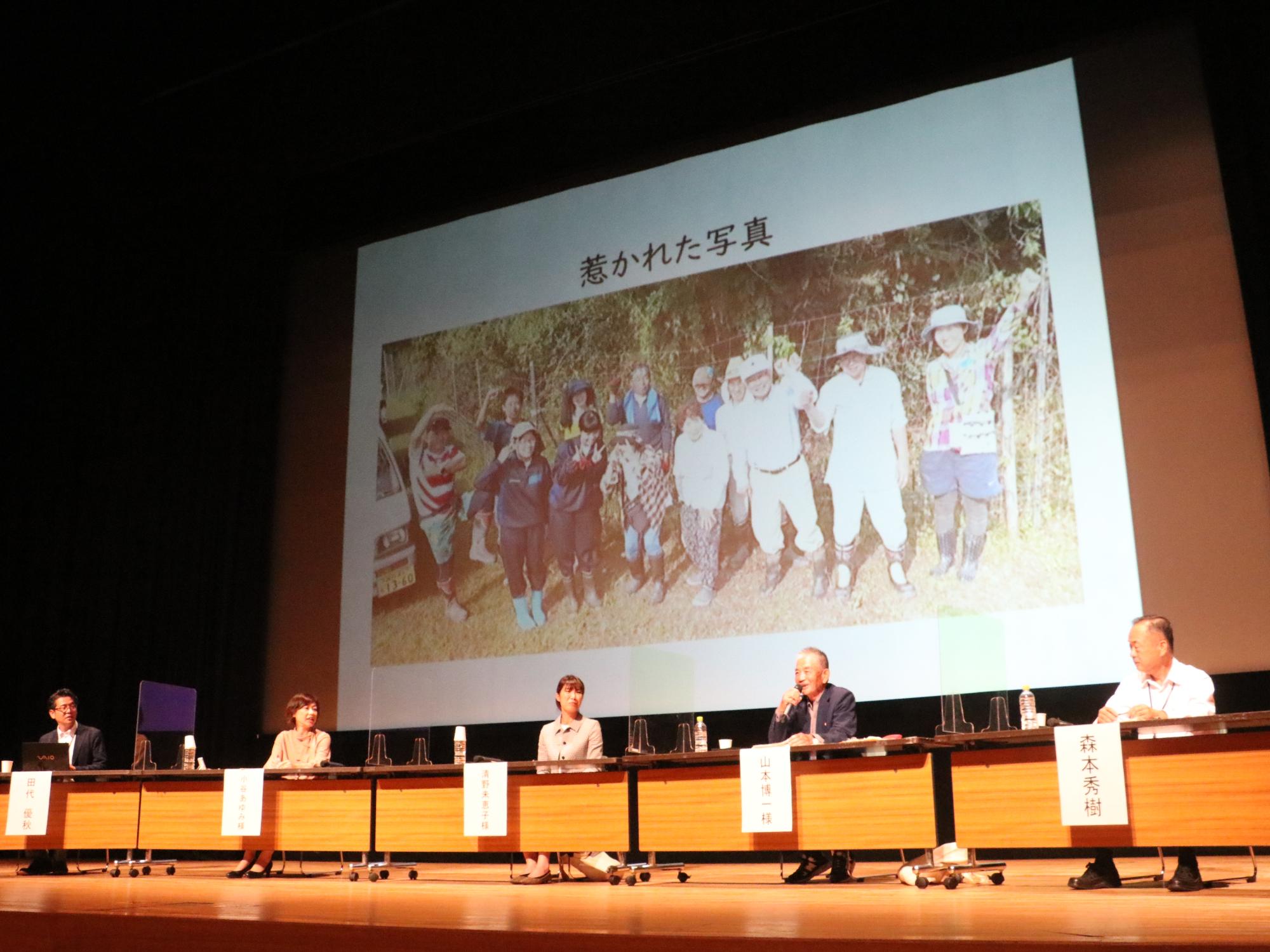 スライドの前にパネラーが座って話されている