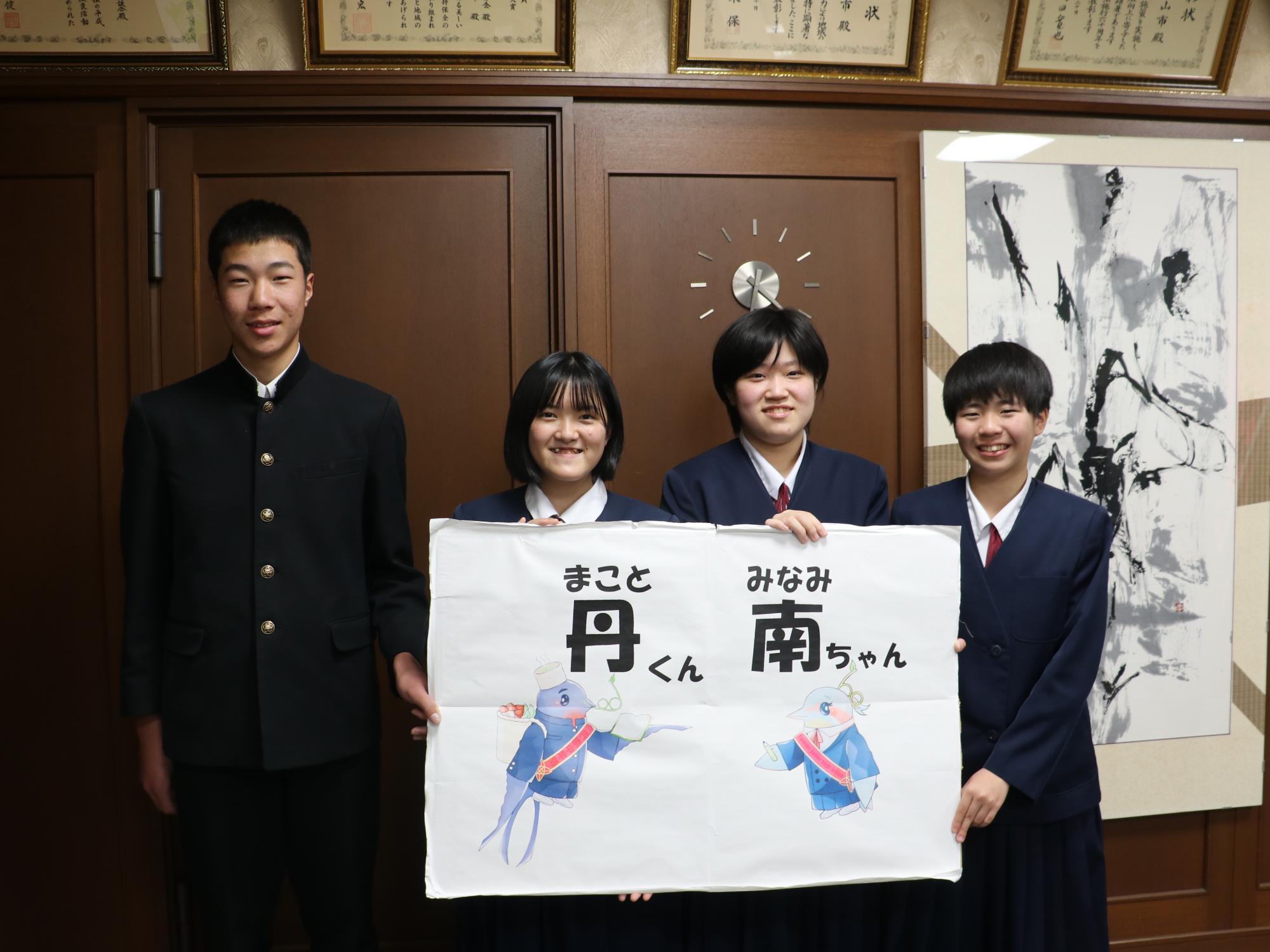 つばめとカワセミをモチーフにしたキャラクターの看板をもった女の子3人と男の子の記念撮影