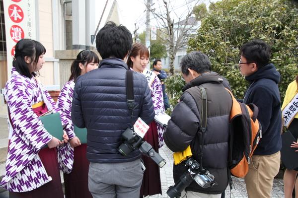 袴を着る丹波篠山観光大使の周りに集まる、カメラを持った男性の写真