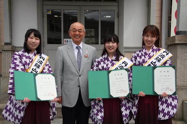 袴を着る丹波篠山観光大使が、笑顔で任命書を持ち、市長を中央にして並んでいる写真