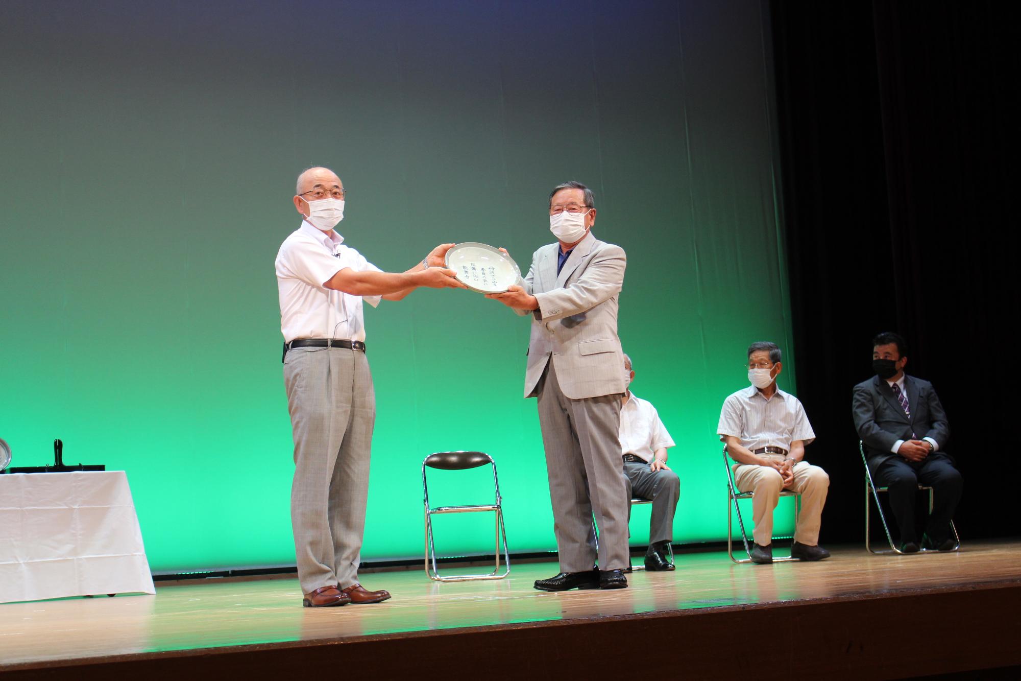 受賞された歌詞が書かれた丹波焼の器を市長と受賞者が一緒に持っている