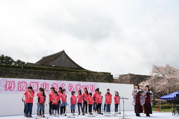 舞台でピンク色のTシャツを着た子供達が紹介されてる写真