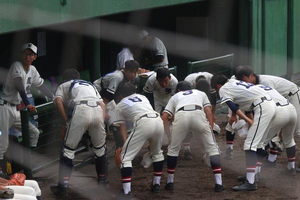 篠山鳳鳴高校軟式野球部の選手たちが、ベンチ前で中腰になり気合を入れている写真