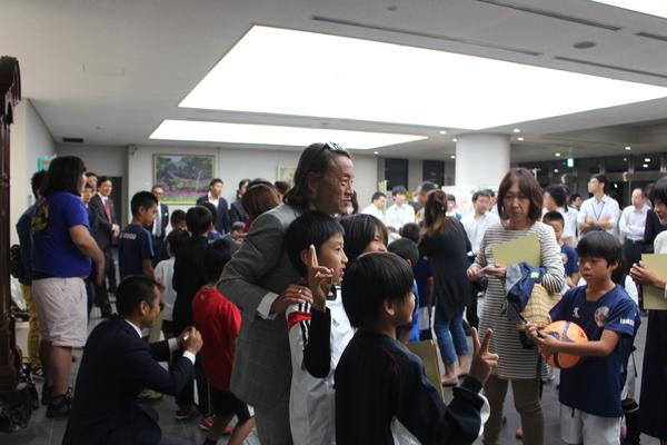 ピースをした少年の肩に北澤選手が手を置いて記念撮影をしている写真