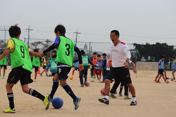 ゼッケン姿の少年2人がボールを蹴っていて、森島選手が声をかけている写真
