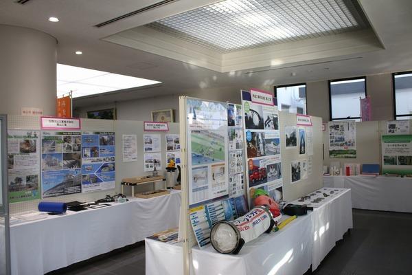 掲示板にたくさんの資料が貼られ、その前にならべられている様々な製品の写真