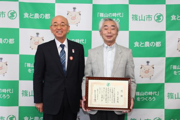 額縁に入った感謝状を持った久下 末男さんと市長との記念写真