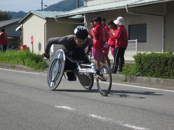 黒のヘルメットをかぶったランナーが懸命に車いすをこいでいる写真