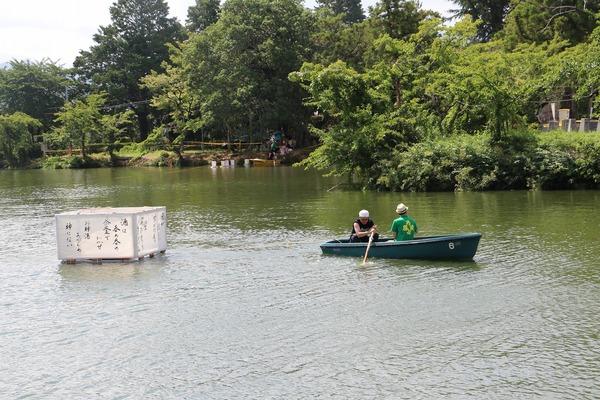 池に設置してある筆で書かれた大きな灯篭の方へ男性2名がボートを漕いでいる様子