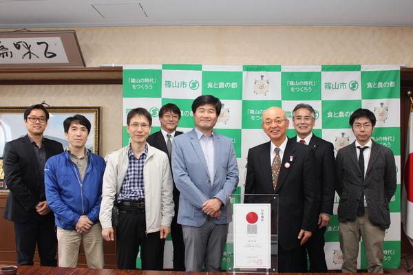 ガラスのフレームに入った認定証を前に、並ぶ韓国文化財庁の方々と市長の集合写真