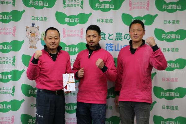 代表の西野 裕彦さんが左手に奨励金、右手でガッツポーズをし、他2名の方が左手でガッツポーズをしている写真