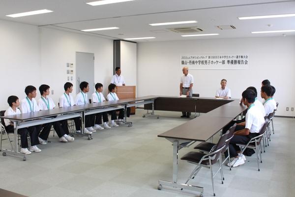 篠山・丹南中学校男子ホッケー部員が座り、市長が立って話をしている写真