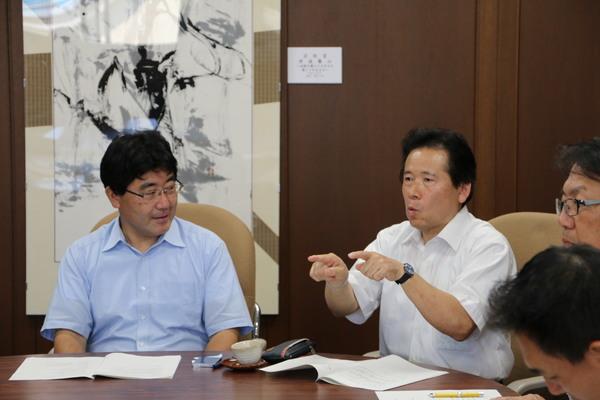 大内 和彦委員が両人差し指で説明していて、その説明を真剣に聞いている嘉田 眞典会長の写真