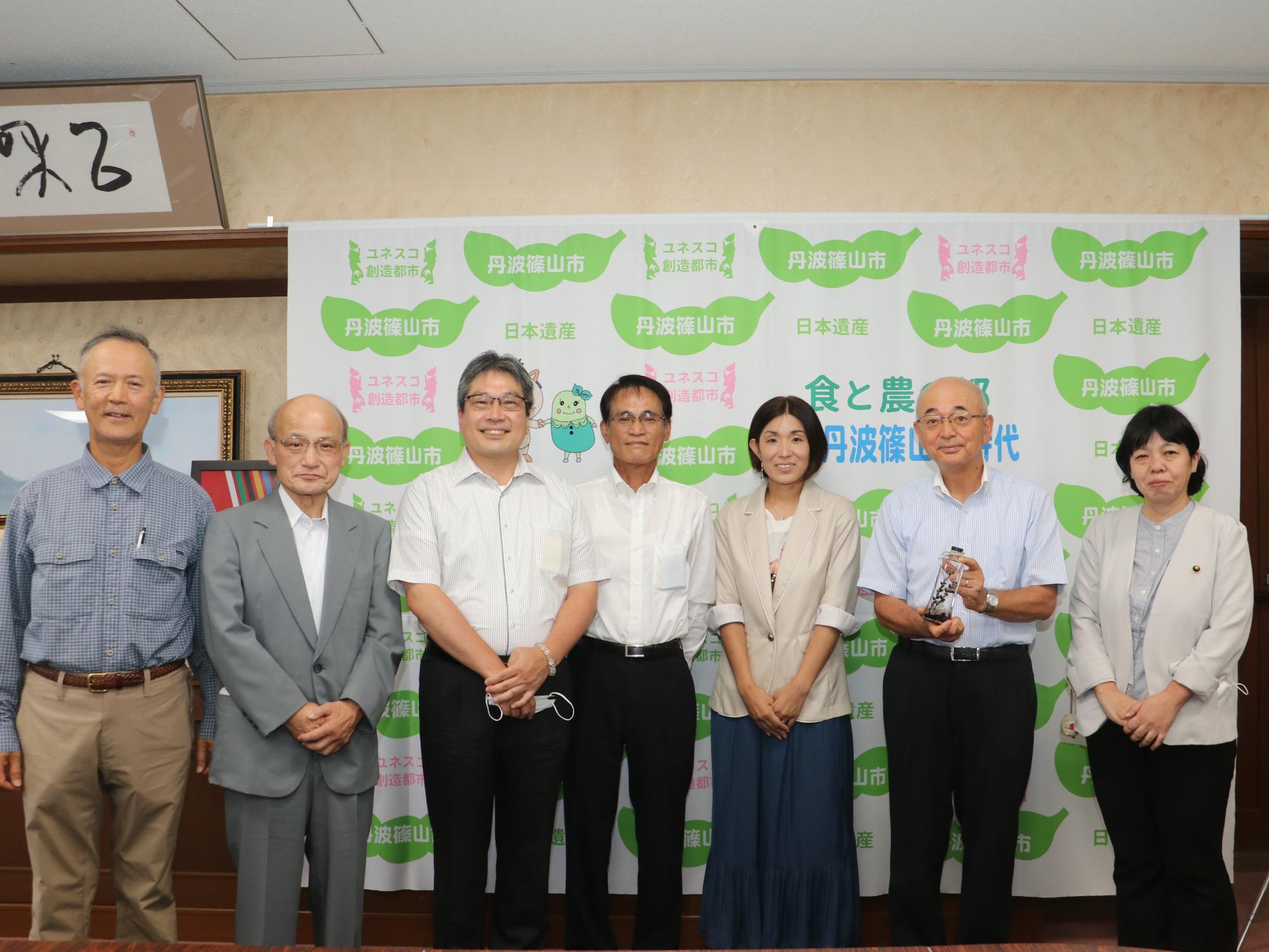 ハーバリウムを持った市長と里山工房の関係者の記念撮影