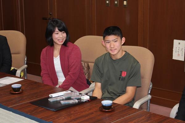 右側に深緑の半袖のティーシャツを着た俣野君、左側にえんじ色のカーデガンを着たお母さんが写っている写真