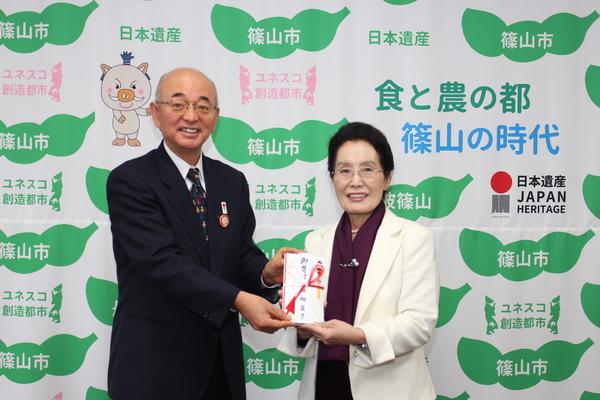 2人で寄付金を持って笑顔で写っている田畑 富子さんと市長の写真
