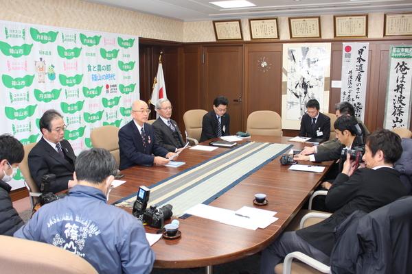 市長がカメラに向かって話をしていて、関係者が数名参加されている写真