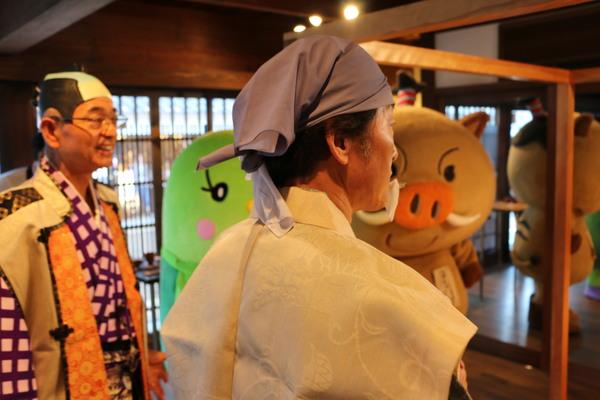 ちょんまげ市長、黄門ちゃま（小山教育部長）の横顔の後ろにゆるキャラがいる写真