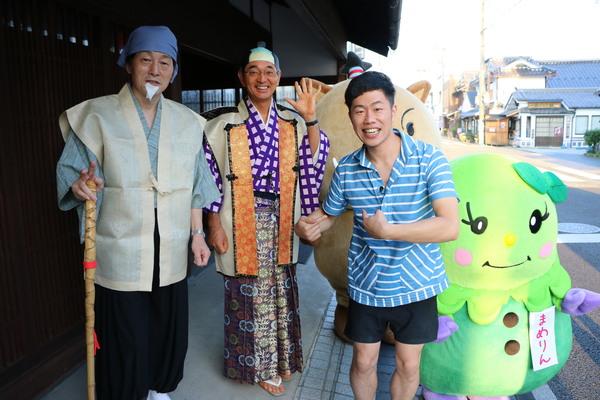 黄門ちゃま（小山教育部長）、左手を上げたちょんまげ市長、吉田裕さん、後ろにゆるキャラが並んだ写真